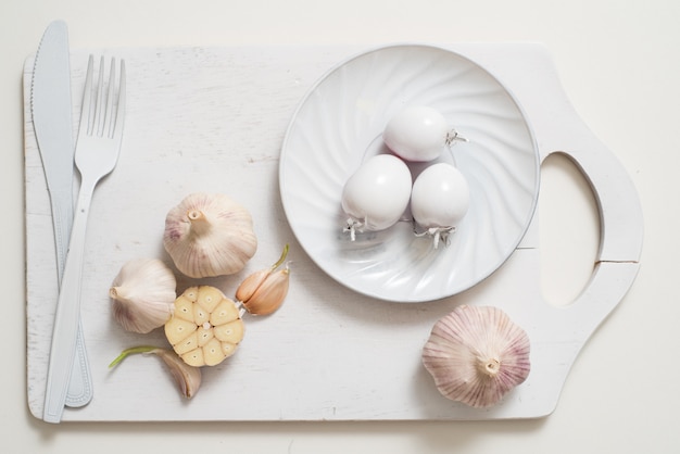 Assiette à fourche blanche sur un vieux plateau en bois avec ail