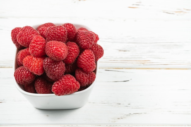 Assiette à la framboise sur fond de bois blanc rustique.