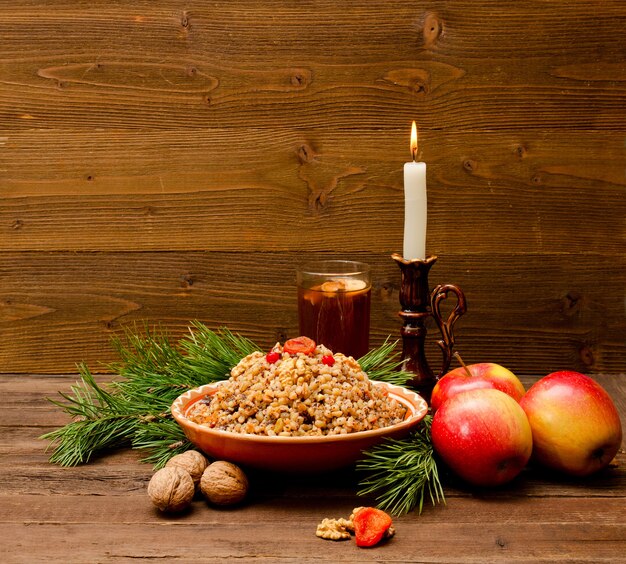 Assiette avec friandises de Noël traditionnelles Slaves la veille de Noël. Compote, branche d'épinette, pommes et bougie sur un fond en bois. Espace pour le texte