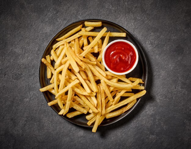 Photo assiette de frites et de ketchup sur une table sombre