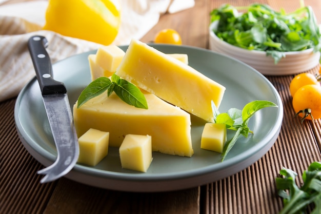 Assiette à fromage avec de délicieuses tranches de fromage et un couteau à fromage, table en bois.