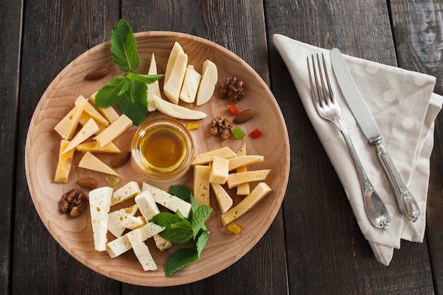 Assiette de fromage avec du miel et des couverts sur bois