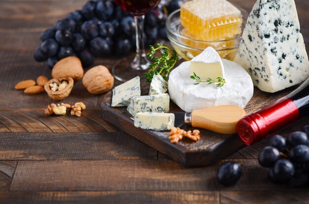 Assiette De Fromage Avec Des Raisins, Miel, Noix Et Vin Rouge Sur Une Table En Bois