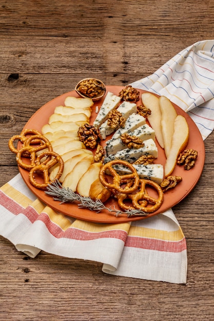 Assiette de fromages antipasti au fromage fumé et bleu, craquelins, miel, noix et poire mûre