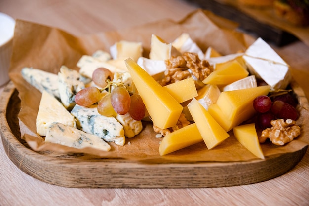 Assiette de fromages aux raisins et aux noix sur une planche de bois Snack de fête Finger food