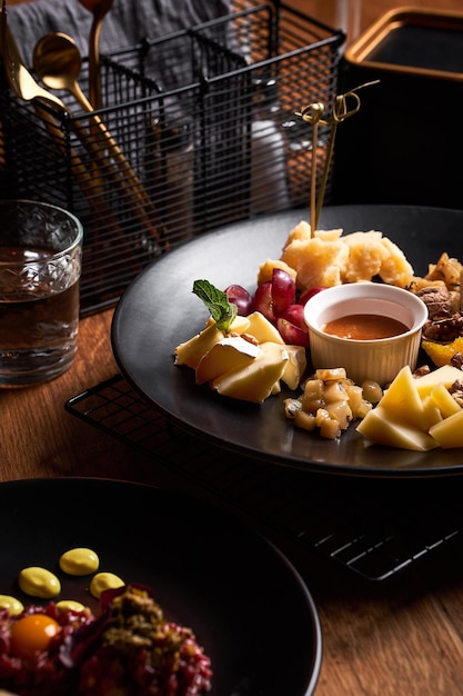 Assiette de fromages aux raisins et miel sur table en bois Tartare de boeuf