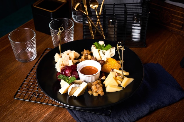 Assiette de fromages aux raisins et miel sur table en bois