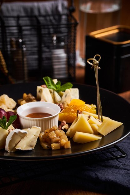 Photo assiette de fromages aux raisins et noix sur table en bois vue rapprochée