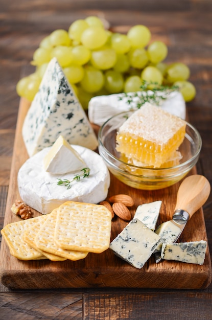 Assiette De Fromages Avec Des Raisins, Des Craquelins, Du Miel Et Des Noix Sur Une Table En Bois