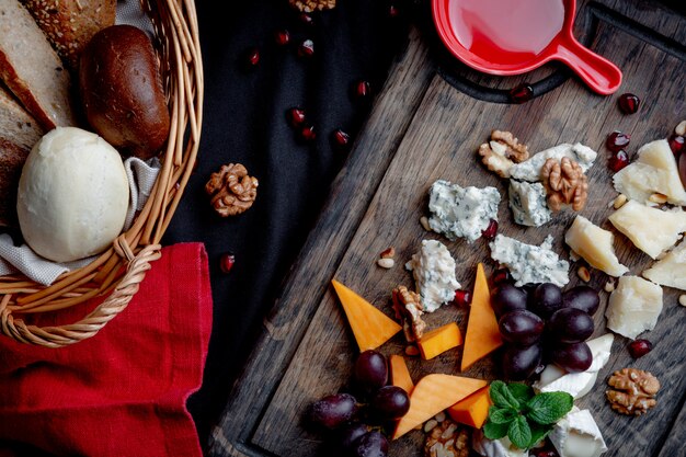 Assiette de fromages servie avec raisins, miel et noix sur un fond en bois. Différents types de fromages