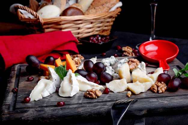 Assiette de fromages servie avec raisins, miel et noix sur une table en bois. Différents types de fromages