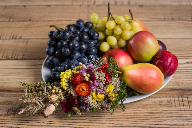 Assiette De Fruits Avec Des Décorations De Fleurs Sauvages Sur La Table En Bois