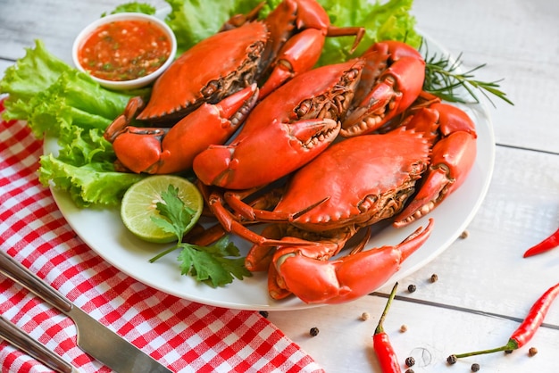 Assiette de fruits de mer aux herbes épices salade de romarin citron vert laitue légume crabe frais sur assiette blanche et sauce aux fruits de mer crabe cuisson des aliments crabe bouilli ou cuit à la vapeur rouge dans la vue de dessus du restaurant