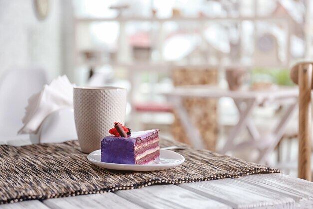 Photo assiette avec un gâteau savoureux et une tasse de thé sur la table au café