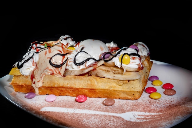 Assiette de gaufres belges avec sauce au caramel à la crème glacée et baies fraîches sur fond sombre