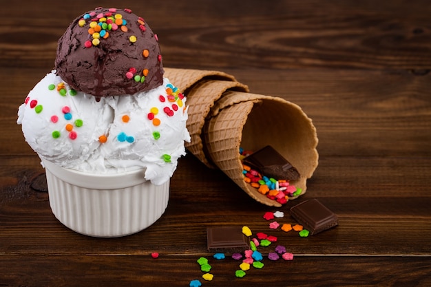 Assiette de glace vanille et chocolat et cuillère à glace swith sprinkles et cornets gaufres sur bois
