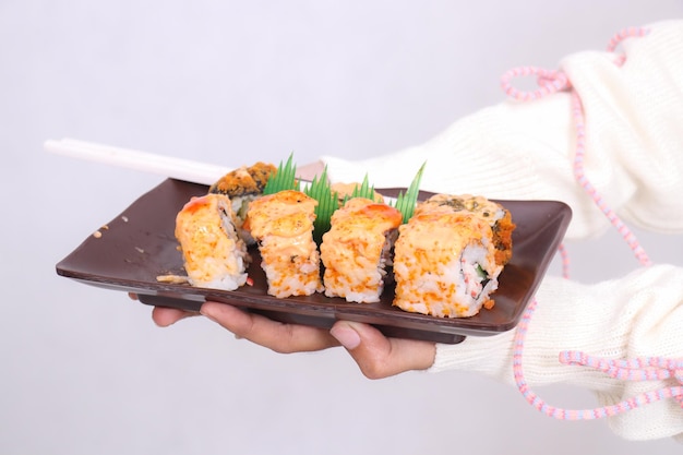 une assiette en gros plan avec un angle avant contenant un plat de sushi, une nourriture japonaise tenue dans les deux mains par une femme