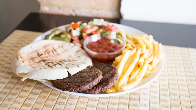 Assiette avec hamburgers, frites et pain pita.