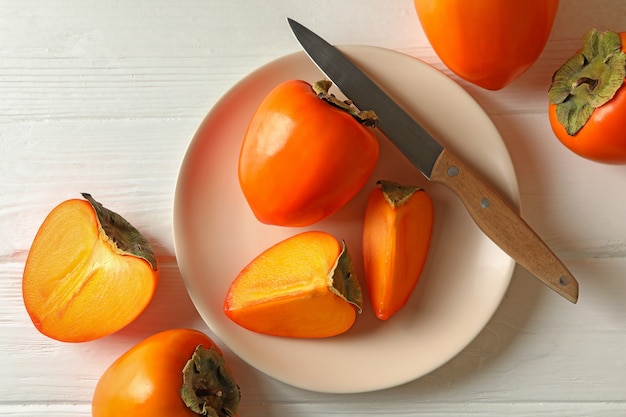 Assiette avec kaki mûr et couteau sur fond de bois