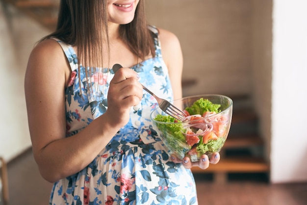 Assiette avec des légumes frais dans les mains d'une femme enceinte