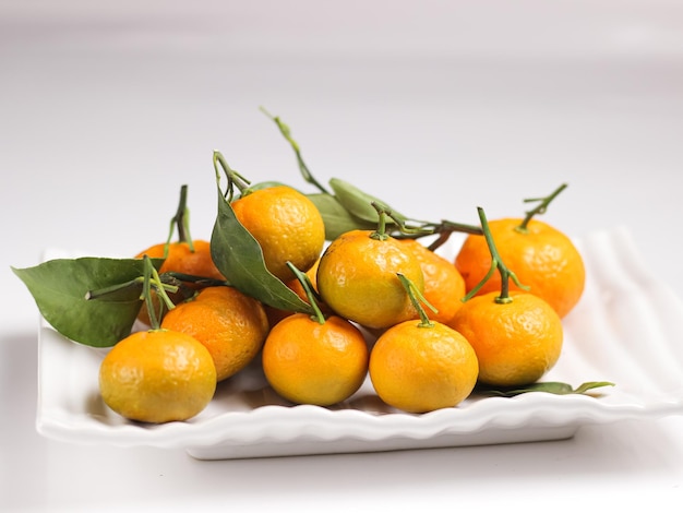 Une assiette de mandarines avec des feuilles sur la tige