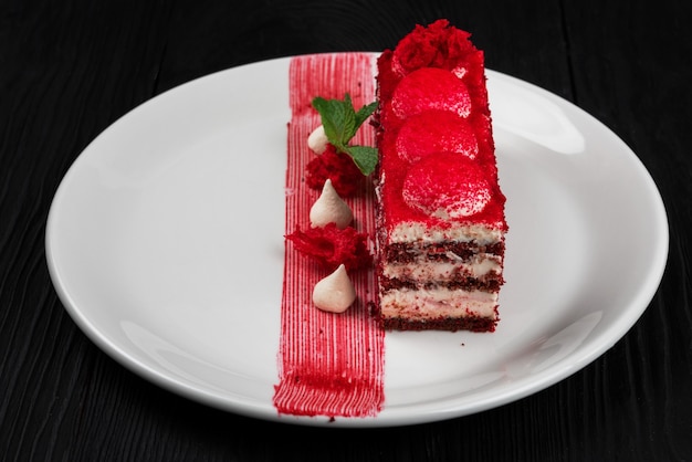 Assiette avec morceau de délicieux gâteau de velours rouge sur fond de bois noir concept de nourriture et de boisson