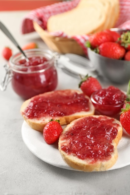 Photo assiette avec des morceaux de pain et de confiture de fraises sur table