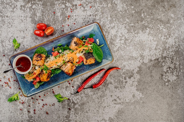 Photo assiette de morceaux de poisson rôtis avec riz pois et légumes menu wok