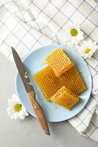 Assiette avec nid d'abeilles et couteau sur fond blanc