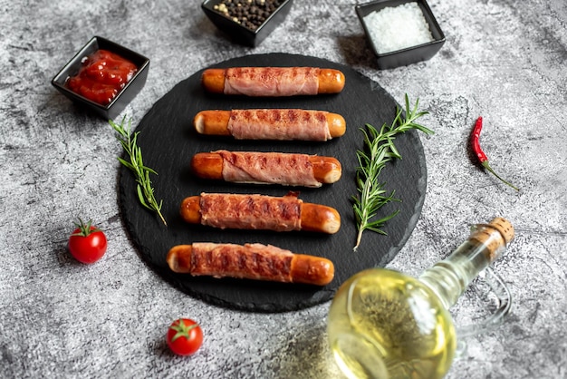 Une assiette noire avec des saucisses enveloppées de bacon dessus