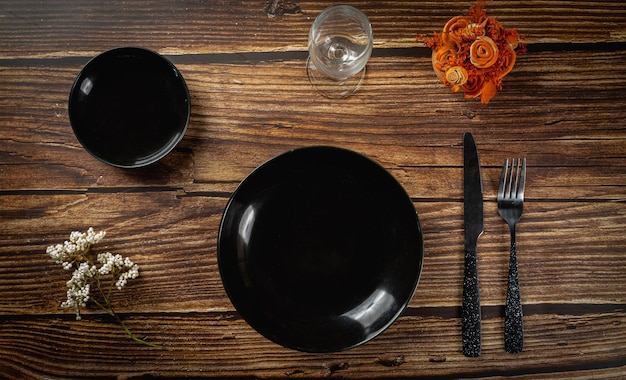 Assiette noire vide et cuillère sur la maquette de la vue de dessus de fond en bois