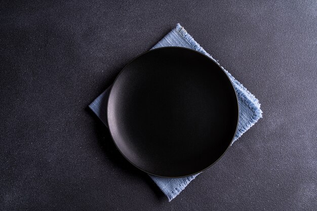 Assiette noire vide sur une serviette sur tableau noir