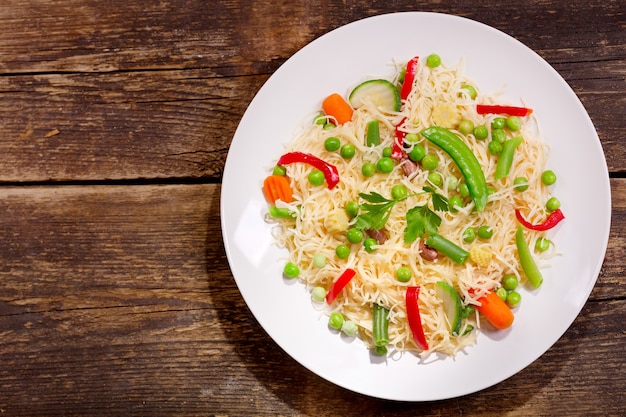 Assiette de nouilles aux légumes sur table en bois, vue du dessus