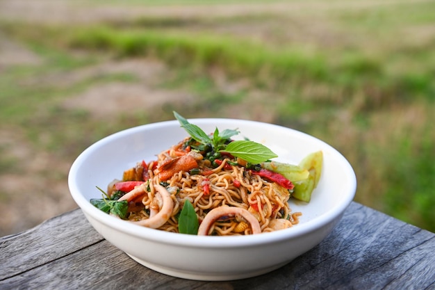 Assiette de nouilles avec des nouilles instantanées sautées avec des légumes herbes épicées savoureuses nouilles asiatiques appétissantes mélange de fruits de mer calmars sautés au basilic et piment