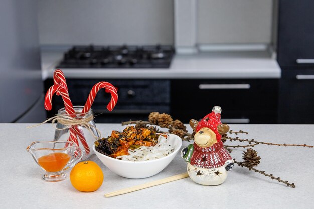 Assiette avec nouilles de riz et poulet Bâtonnets alimentaires Décoration festive Fond de cuisine maison sombre Concept de Noël