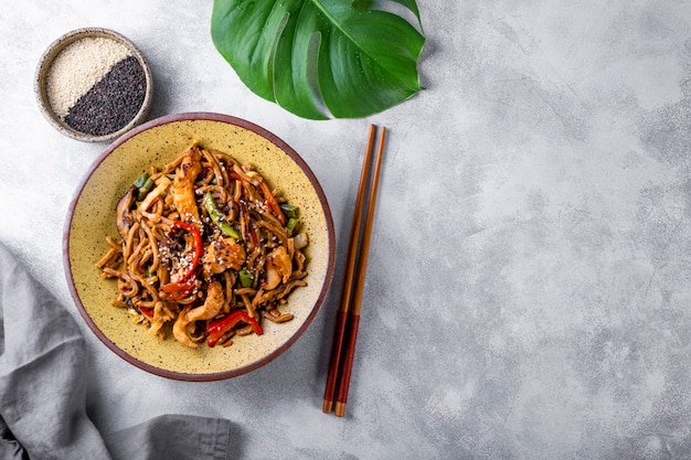 Assiette de nouilles soba de sarrasin asiatiques avec légumes, champignons et poulet sur fond gris clair