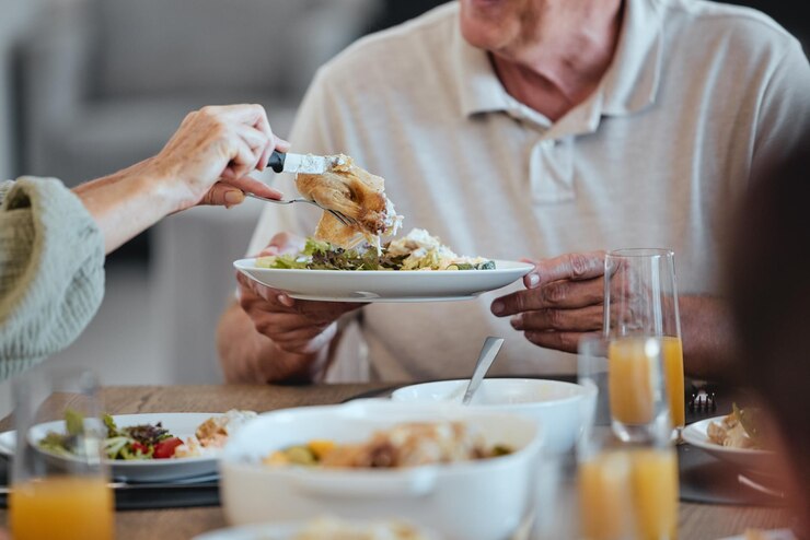 Photo assiette de nourriture et action de grâces avec un repas entre les mains d'un homme âgé lors d'un déjeuner en famille pour la célébration fête santé et sociale avec un groupe de personnes mangeant ensemble pendant la période des fêtes