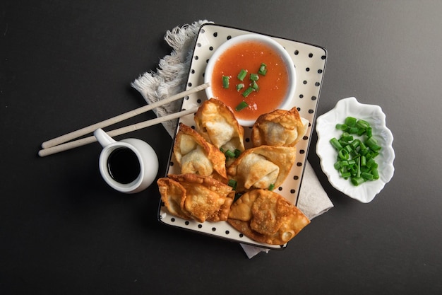 Une assiette de nourriture avec des baguettes et un bol d'oignons verts.