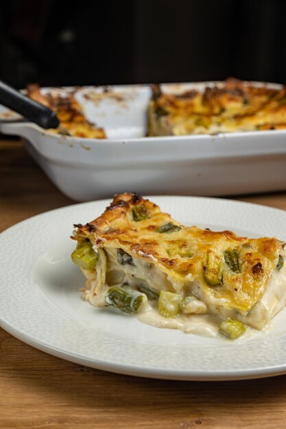 Une assiette de nourriture avec une cocotte de lasagnes au poulet et aux légumes.