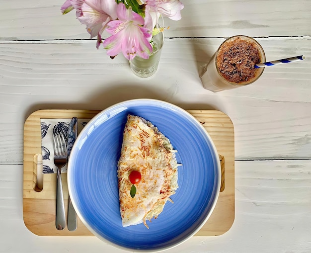 Une assiette de nourriture avec une paille et une tasse de café sur un plateau en bois.