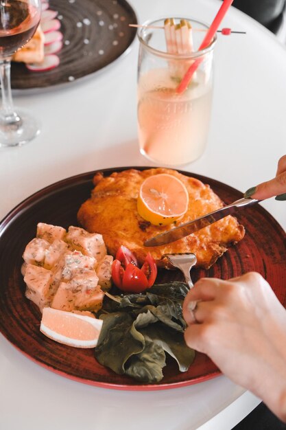 une assiette de nourriture avec une personne coupant un couteau et un verre d'eau