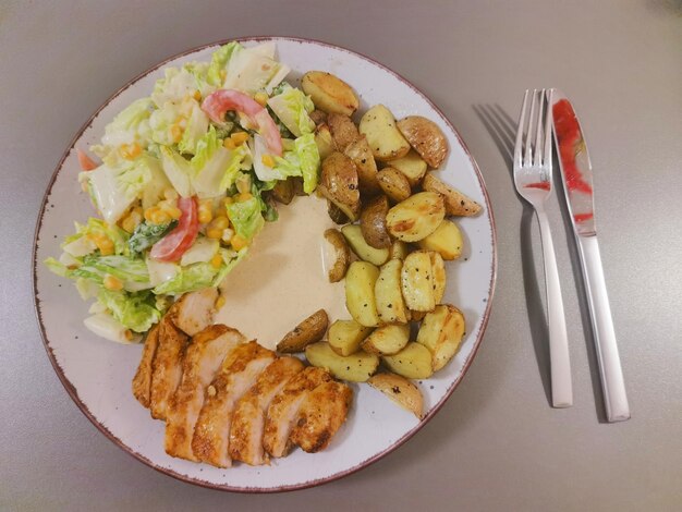 Une assiette de nourriture avec une salade et une fourchette à côté.