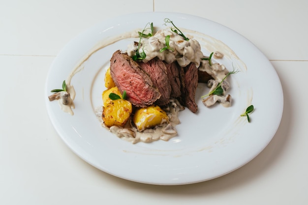 Une assiette de nourriture avec un steak et des pommes de terre dessus