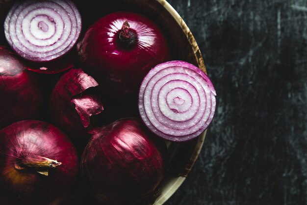 Assiette avec oignon violet. Oignons avec des gouttelettes d'eau. Sur la table, une pelure d'oignon éparpillée. Petit déjeuner pour un végétarien