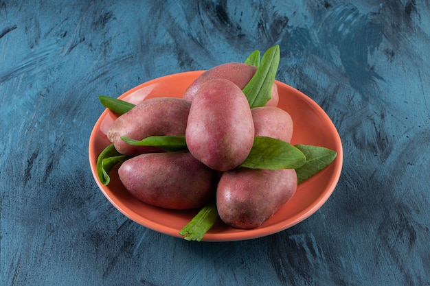 Assiette orange de patates douces biologiques sur surface bleue.