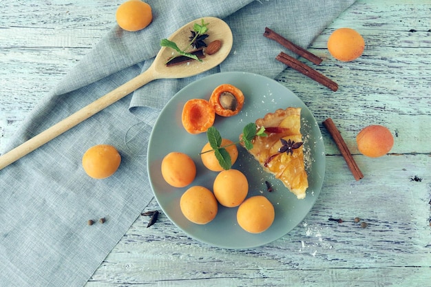 Une assiette d'oranges avec une tranche de tarte dessus et une cuillère en bois sur la table