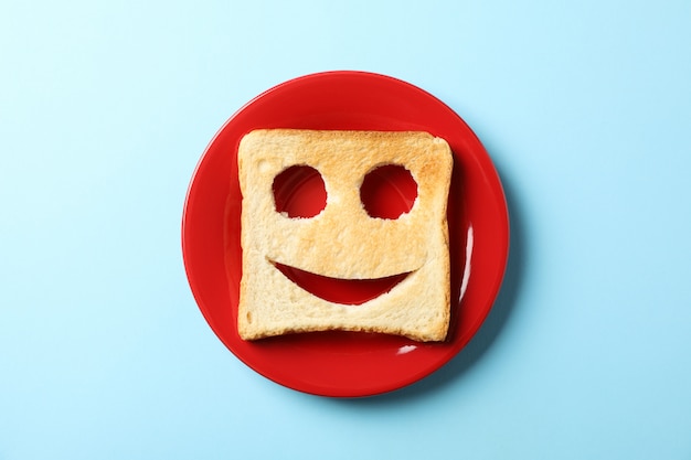 Assiette et pain grillé avec visage heureux sur bleu, vue de dessus