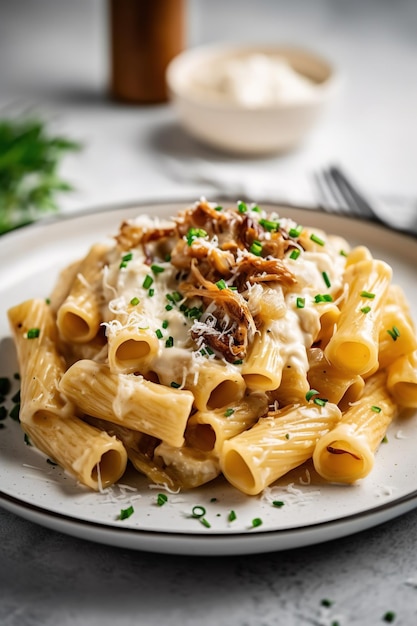 Une assiette de pâtes avec une sauce blanche et du fromage dessus.