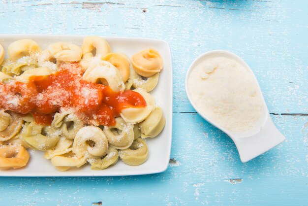 Assiette de pâtes tortellini italiennes avec du fromage râpé servi sur la table