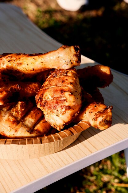 une assiette avec des pattes de poulet grillées marinées se tient sur une table en nature en gros plan